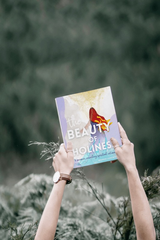 Beauty of Holiness book by Sharon Longworth being held outside